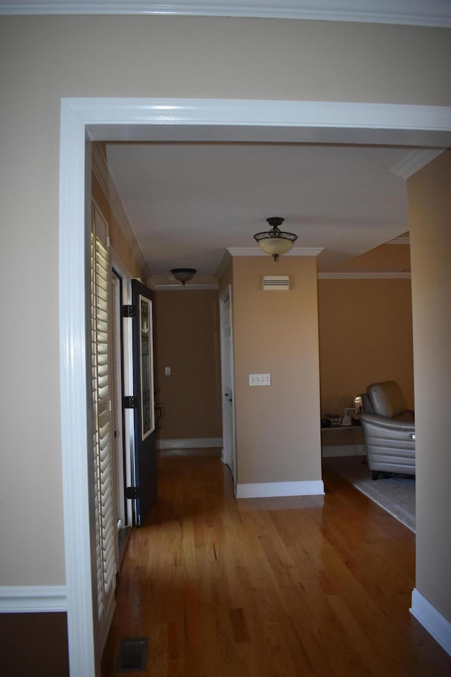 corridor with visible vents, baseboards, ornamental molding, and light wood finished floors