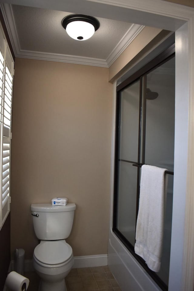 bathroom with tile patterned flooring, baseboards, toilet, ornamental molding, and a textured ceiling