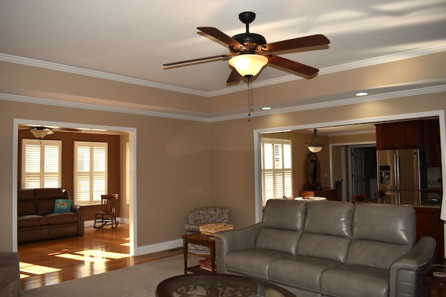 living area with plenty of natural light, wood finished floors, and ornamental molding