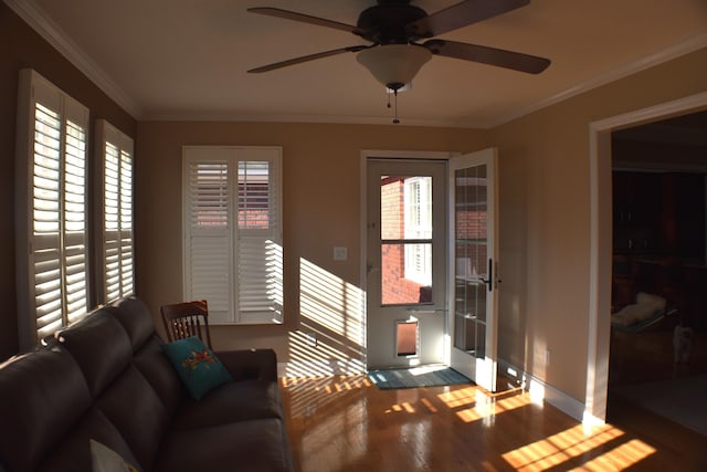 living room with ceiling fan, baseboards, wood finished floors, and ornamental molding