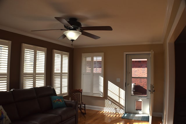 living room with wood finished floors, a ceiling fan, baseboards, and ornamental molding