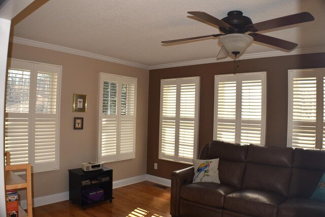 living room with visible vents, crown molding, a ceiling fan, and wood finished floors