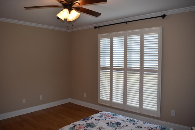 unfurnished bedroom with a ceiling fan, crown molding, baseboards, and wood finished floors