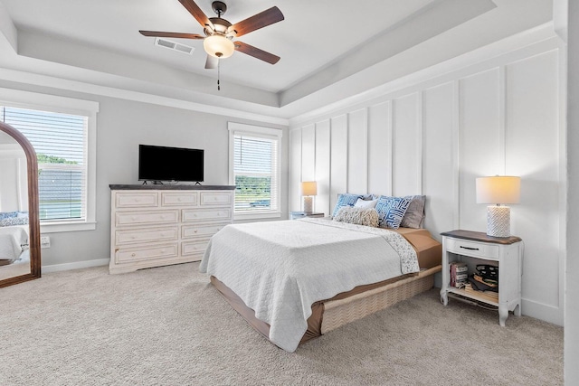 bedroom featuring a tray ceiling, ceiling fan, and light carpet