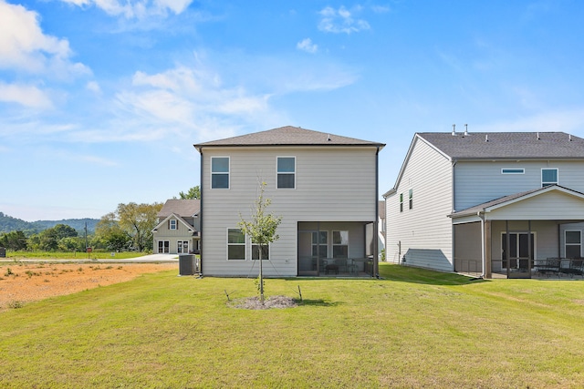 rear view of property featuring a lawn, central AC, and a sunroom