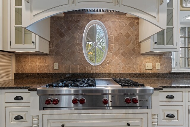 kitchen featuring decorative backsplash, white cabinetry, stainless steel cooktop, and dark stone counters