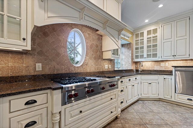 kitchen with dark stone countertops, decorative backsplash, light tile patterned flooring, and appliances with stainless steel finishes