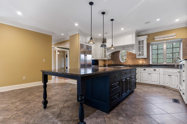 kitchen with tasteful backsplash, built in refrigerator, a center island, and white cabinets