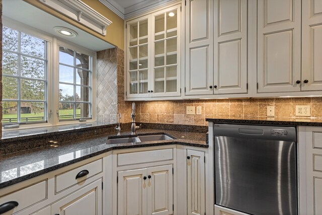 kitchen featuring dishwasher, dark stone counters, sink, ornamental molding, and white cabinetry