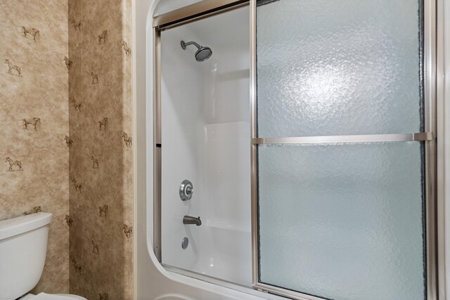 bathroom featuring toilet and enclosed tub / shower combo