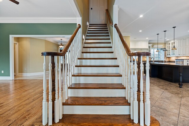 staircase featuring wood-type flooring and ornamental molding