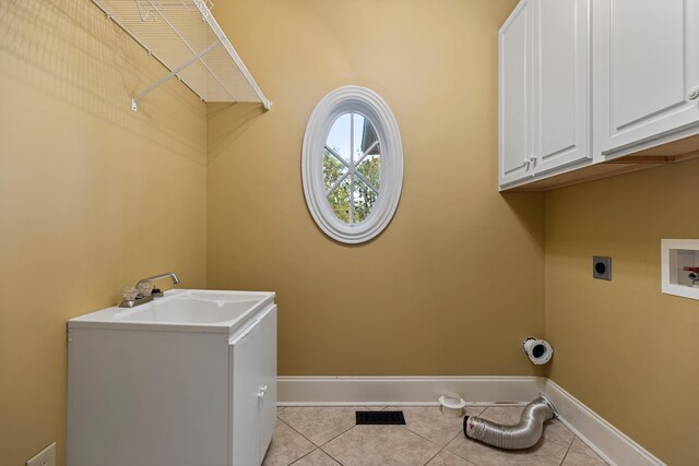 clothes washing area with electric dryer hookup, cabinets, sink, washer hookup, and light tile patterned floors