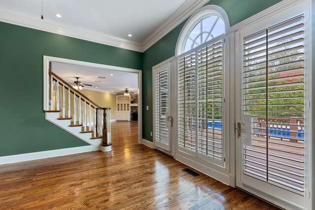 foyer with wood-type flooring, crown molding, ceiling fan, and a healthy amount of sunlight