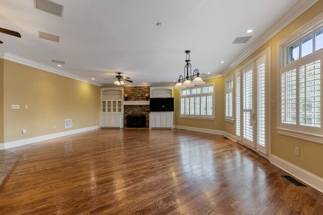 unfurnished living room featuring a stone fireplace, ceiling fan, dark wood-type flooring, and ornamental molding