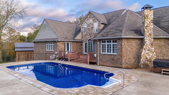 pool at dusk featuring a wooden deck