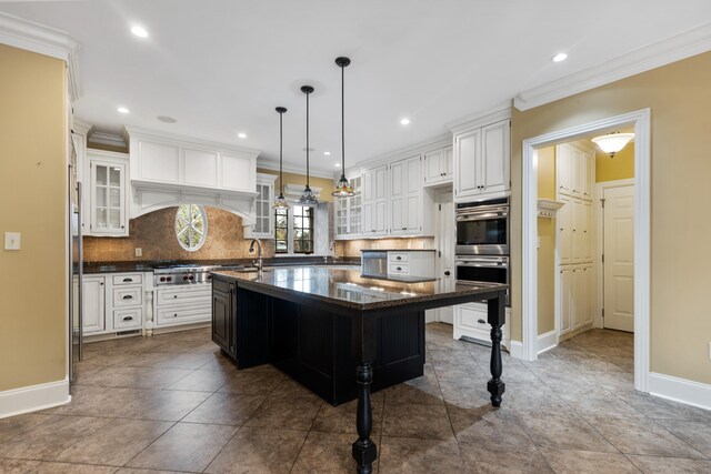 kitchen featuring a kitchen bar, backsplash, white cabinets, hanging light fixtures, and a large island