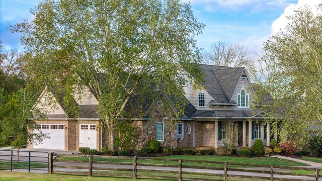 cape cod home featuring a garage and a front lawn