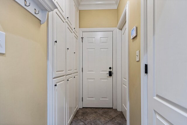 doorway to outside with dark tile patterned floors and crown molding