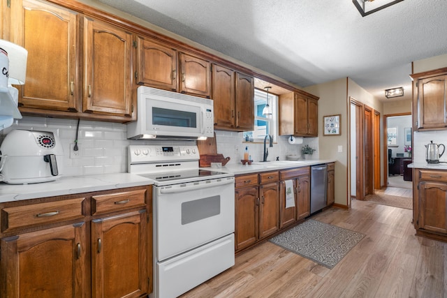 180 Mapleton Forest Dr NW, Cleveland, TN 37312 - kitchen with white appliances, light wood-type flooring, backsplash, brown cabinetry, and a textured ceiling