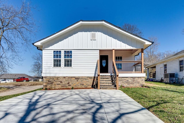 view of front facade featuring a porch, a front yard, and board and batten siding