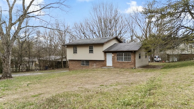 back of house with brick siding and a yard