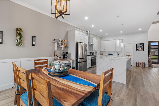 dining room featuring a chandelier, sink, light hardwood / wood-style floors, and ornamental molding