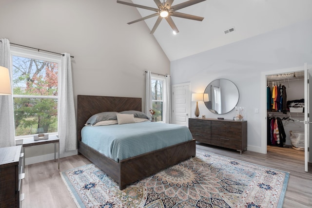 bedroom with a closet, light hardwood / wood-style floors, high vaulted ceiling, and ceiling fan