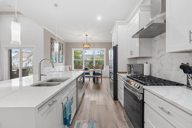 kitchen with white cabinets, a center island with sink, wall chimney range hood, and appliances with stainless steel finishes