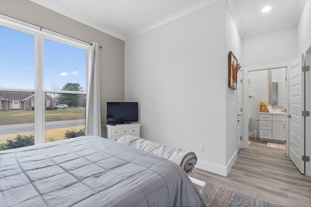 bedroom featuring ornamental molding, light hardwood / wood-style flooring, and ensuite bath