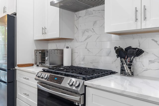 kitchen with appliances with stainless steel finishes, white cabinetry, wall chimney exhaust hood, and light stone counters