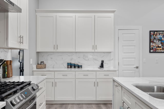 kitchen with white cabinetry, light stone counters, and wall chimney range hood