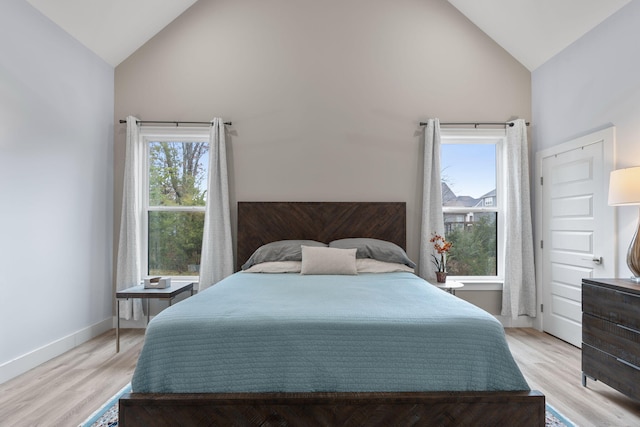 bedroom with light hardwood / wood-style floors, high vaulted ceiling, and multiple windows