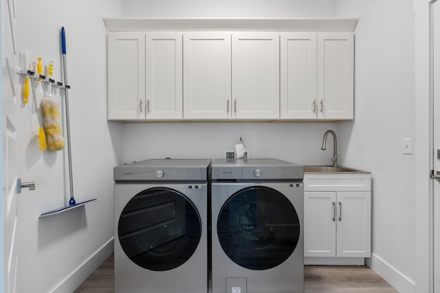 washroom featuring sink, wood-type flooring, cabinets, and independent washer and dryer