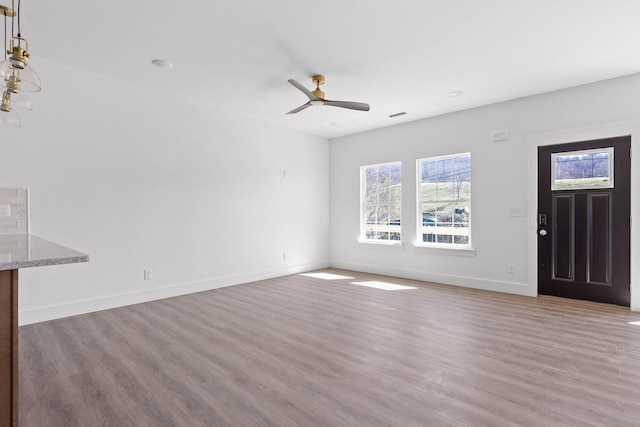 unfurnished living room featuring a ceiling fan, baseboards, visible vents, and light wood finished floors