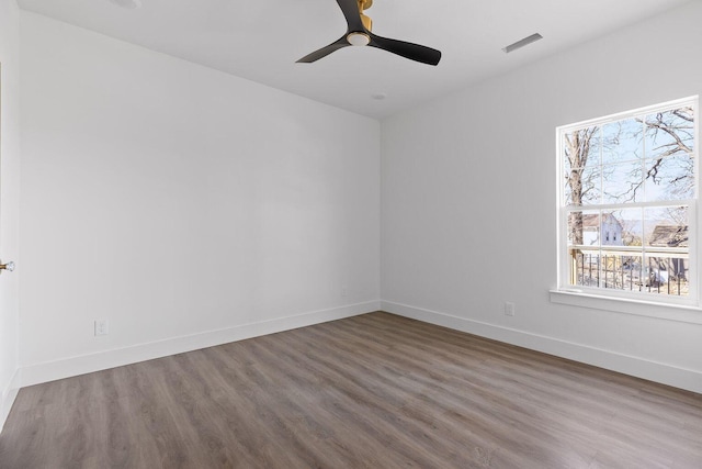 spare room featuring a ceiling fan, visible vents, baseboards, and wood finished floors
