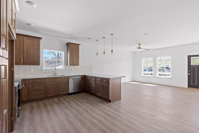 kitchen with light countertops, appliances with stainless steel finishes, open floor plan, a sink, and a peninsula