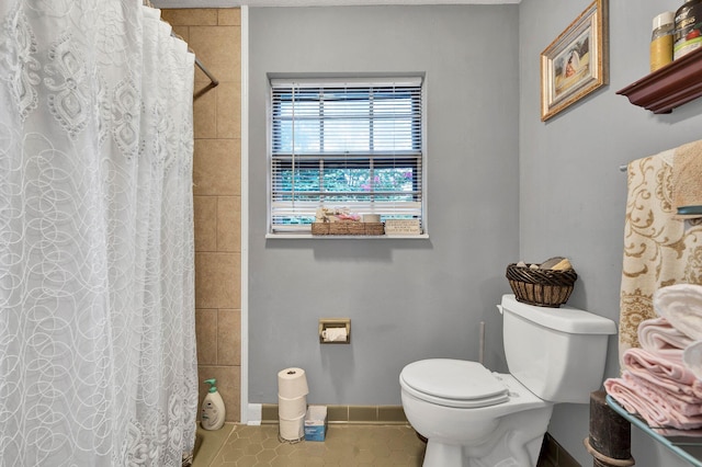 bathroom with a shower with curtain, tile patterned floors, and toilet