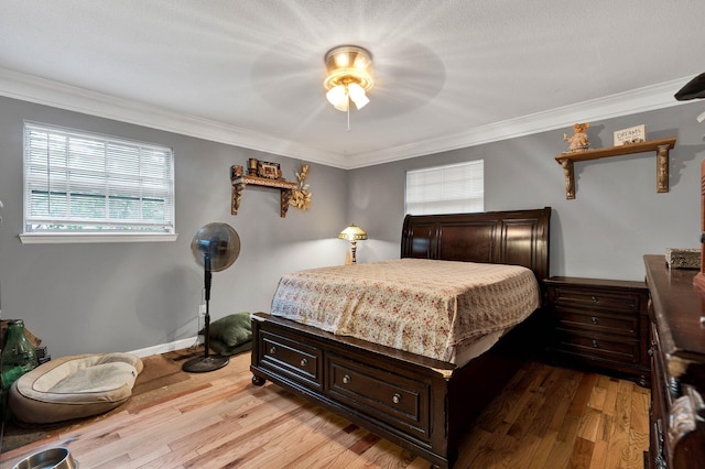 bedroom with ceiling fan, ornamental molding, and light wood-type flooring