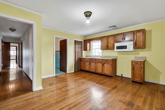 2408 Peerless Rd NW, Cleveland, TN 37311 - kitchen featuring white microwave, baseboards, hardwood / wood-style flooring, light countertops, and crown molding