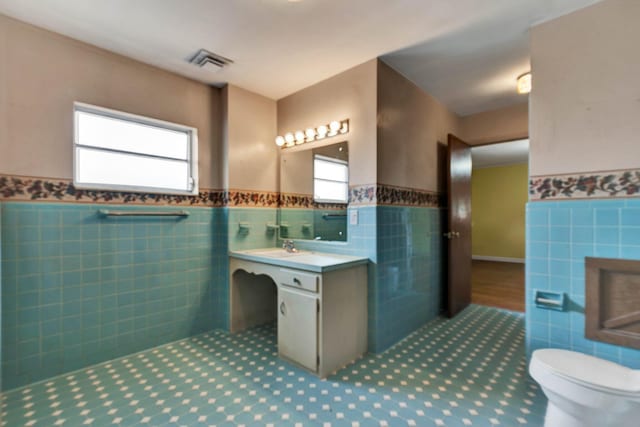 2408 Peerless Rd NW, Cleveland, TN 37311 - bathroom with visible vents, toilet, vanity, wainscoting, and tile walls