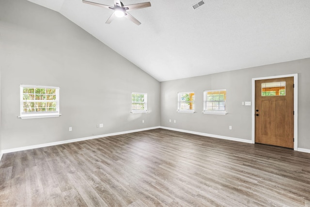 unfurnished living room with a wealth of natural light, wood-type flooring, and lofted ceiling