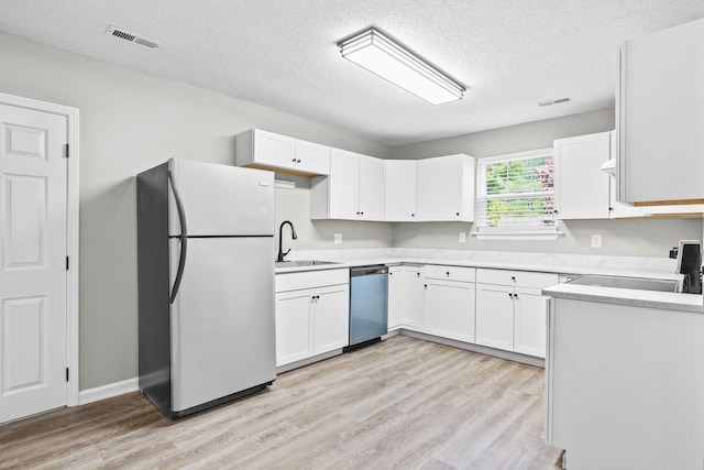 kitchen with a textured ceiling, sink, white cabinetry, and stainless steel appliances