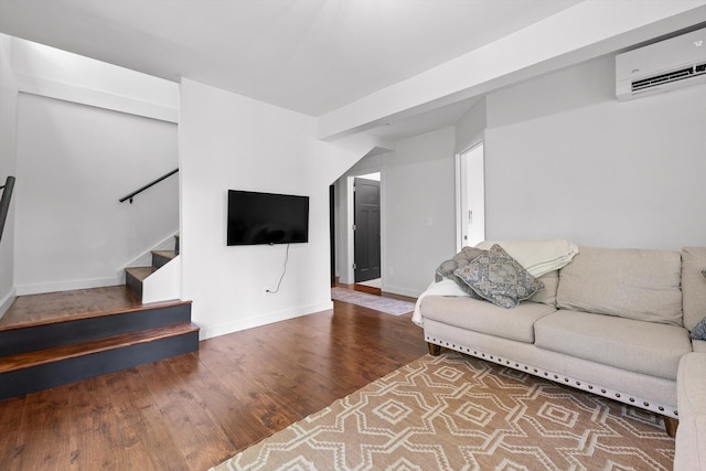 living room featuring stairway, baseboards, a wall unit AC, and wood finished floors