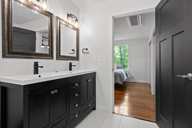 full bath with double vanity, baseboards, visible vents, and a sink