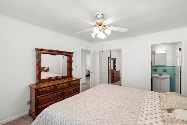 carpeted bedroom with a closet, ensuite bath, and ceiling fan