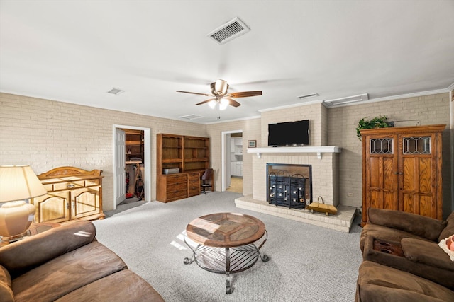 carpeted living room featuring crown molding, ceiling fan, brick wall, and a brick fireplace