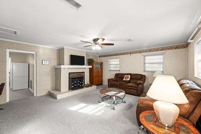 carpeted living room featuring ceiling fan, ornamental molding, brick wall, and a brick fireplace