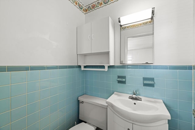 bathroom featuring vanity, toilet, and tile walls