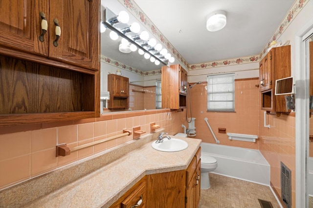 full bathroom featuring vanity, tiled shower / bath, decorative backsplash, toilet, and tile walls