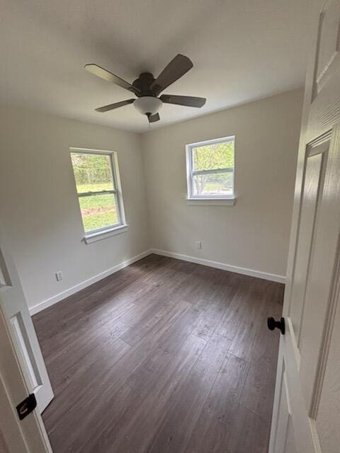 empty room featuring baseboards, a ceiling fan, and dark wood-style flooring